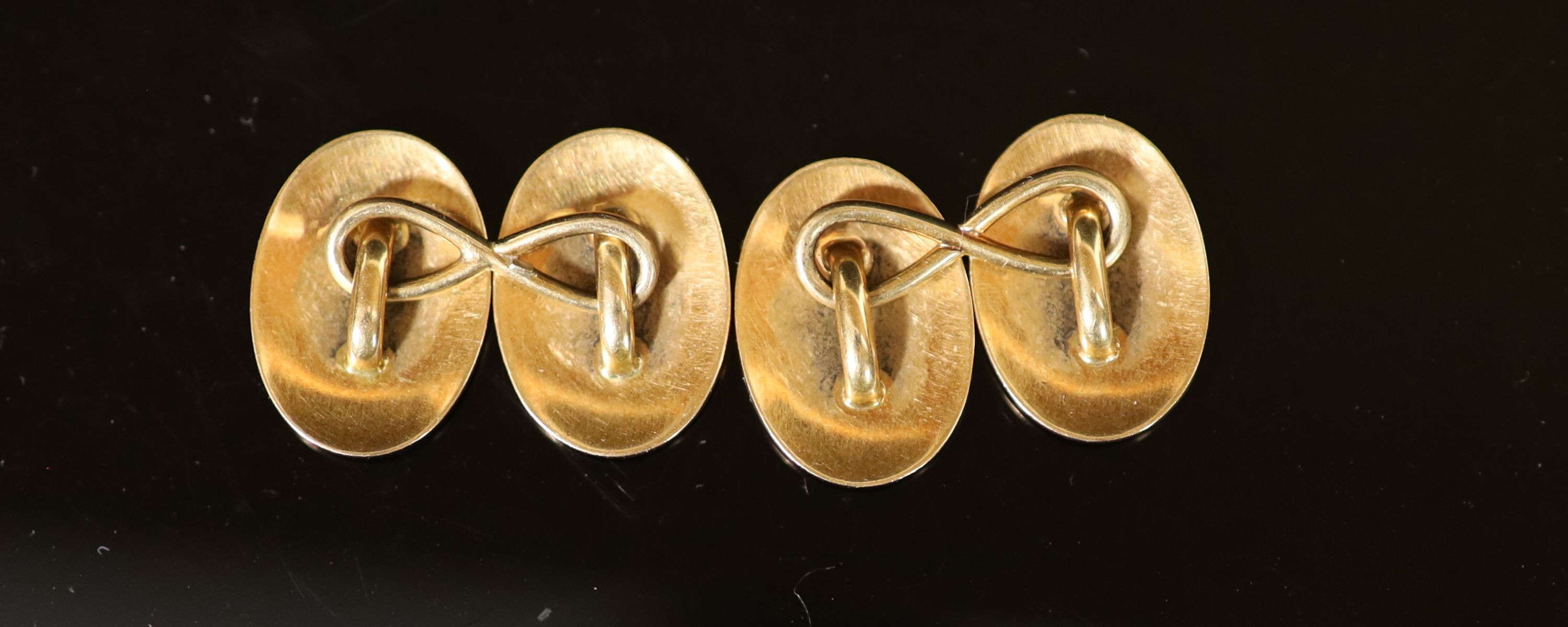 A pair of gold and white enamel oval cufflinks, each gilded with Prince of Wales Feathers and monogram below a coronet
